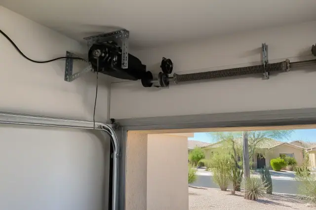 Wall-mounted garage door opener installation with tracks and wiring in a Phoenix, AZ garage.
