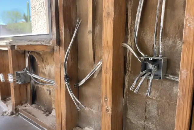 Contractor photo of old metal wires being extracted from an open wall cavity during rewiring in Peoria, AZ.