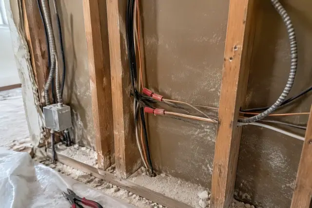 Contractor photo of copper circuit replacement and old cables in an open wall in Phoenix, AZ.