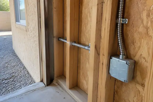 Heavy-gauge armored cable secured to a wall framing with metal straps for a residential circuit installation in Peoria, AZ.