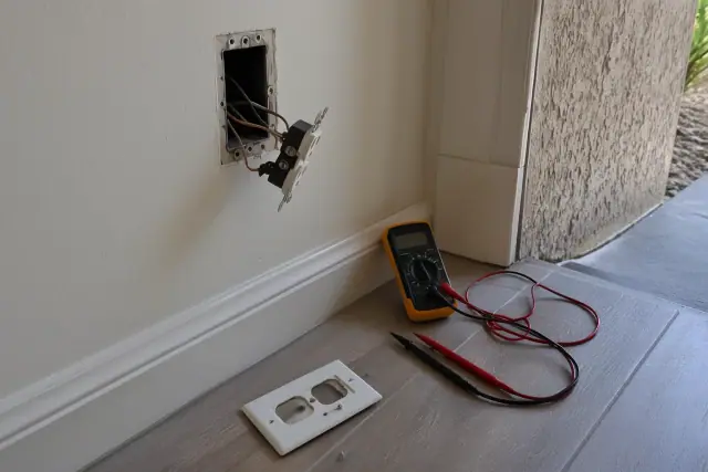 Electrical safety inspection showing exposed copper wires and a multimeter in a Phoenix, AZ home.