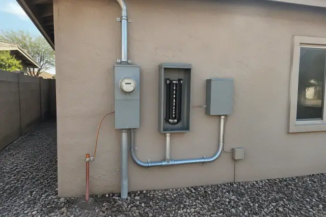 Electrical service mast, meter socket, and grounding on a stucco wall in Phoenix, AZ.
