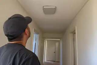 Technician observing a newly closed electrical junction box on a stucco hallway wall in Phoenix, AZ.