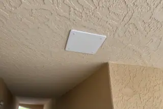 Secured cover plate on a hallway ceiling junction box with desert wall texture in Phoenix, AZ.