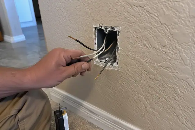 Electrician inspecting exposed wiring inside a junction box in Phoenix, AZ.