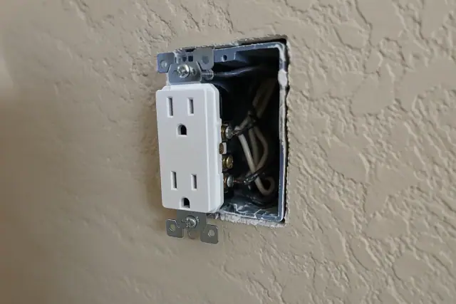 Tamper-resistant duplex electrical receptacle on a beige stucco wall in Avondale, AZ.
