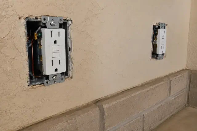 GFCI receptacles wired on a beige stucco wall during an electrical upgrade in Phoenix, AZ.