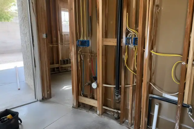 Kitchen and bathroom rewiring progress showing exposed wire bundles on wooden studs in a Phoenix, AZ home.