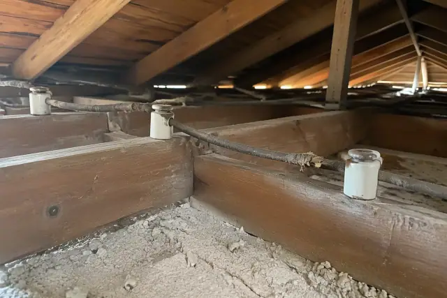 Knob and tube wiring with vintage ceramic insulators above a plaster ceiling in Phoenix, AZ.