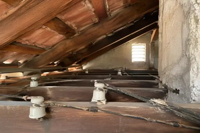 Attic space in Glendale, AZ showing old porcelain knob insulators and frayed wires during a whole house rewiring.