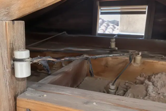 Knob and tube wiring with peeling insulation in an attic during a whole house rewiring in Goodyear, AZ.