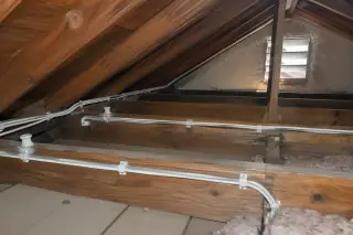 New NM-B cables secured along attic wooden framing next to vintage ceramic insulators in Phoenix, AZ.