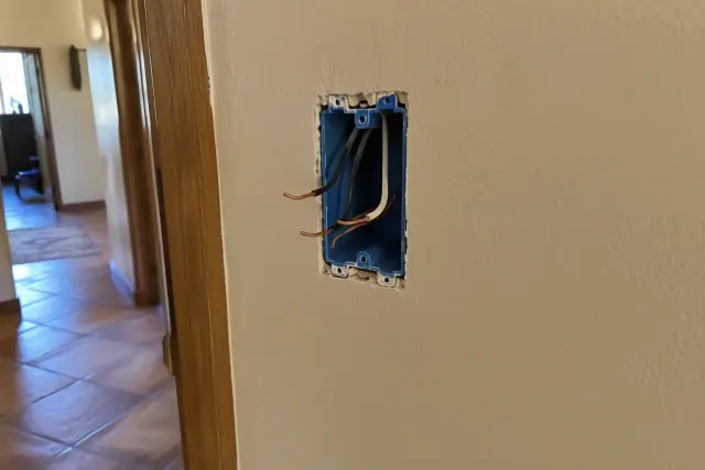 Drywall cutout showing an electrical box with stripped wires for a switch in Scottsdale, AZ.