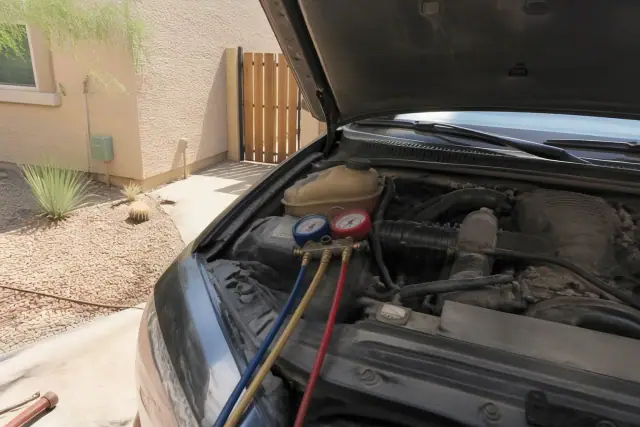 Manifold gauges connected to a vehicle's AC system during diagnostic testing at a residence in Phoenix, AZ.