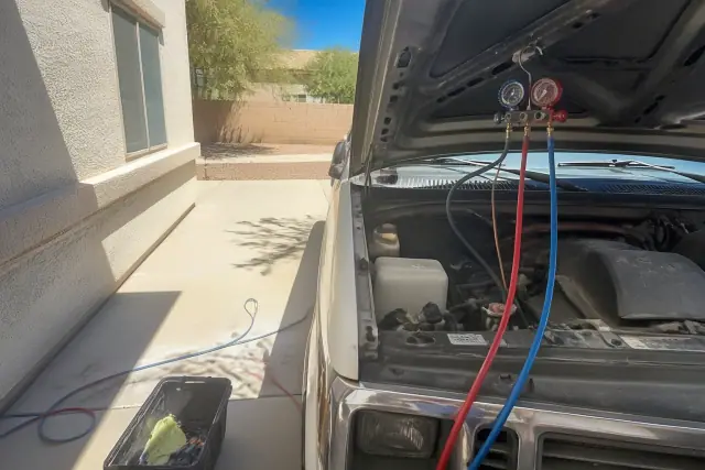 Mobile mechanic performing an AC repair on a vehicle in a residential driveway in Chandler, AZ.