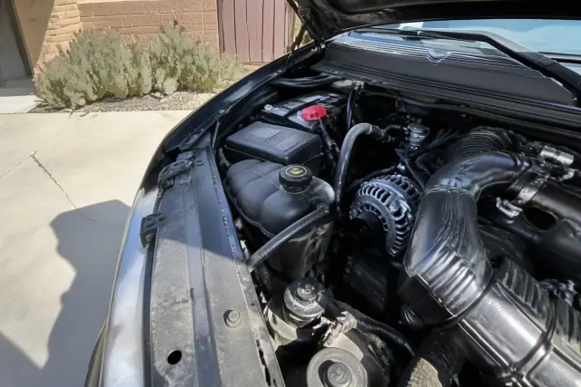 New alternator installed in a car with an open hood on a concrete driveway in Glendale, AZ.