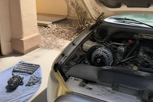 A mobile mechanic performs an alternator replacement on a vehicle parked on a concrete pad in Chandler, AZ.