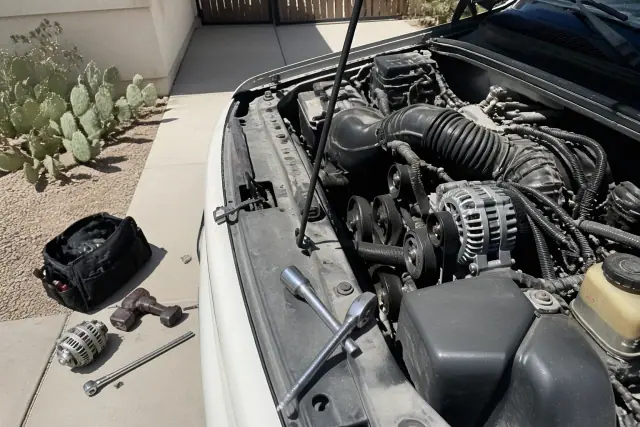 A mobile mechanic replacing an alternator on a car in a driveway in Goodyear, AZ.