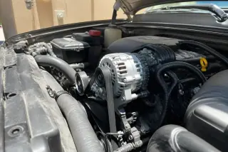 New alternator and clean belts installed in an open engine bay under desert sunlight in Phoenix, AZ.