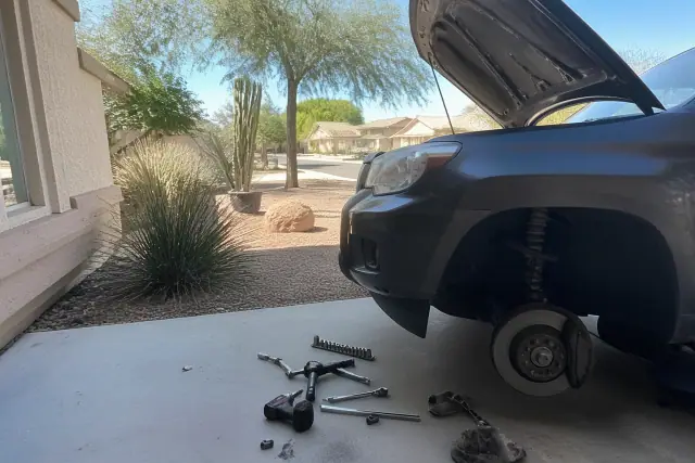 Mobile mechanic performing brake repair on a car in a residential driveway in Mesa, AZ.