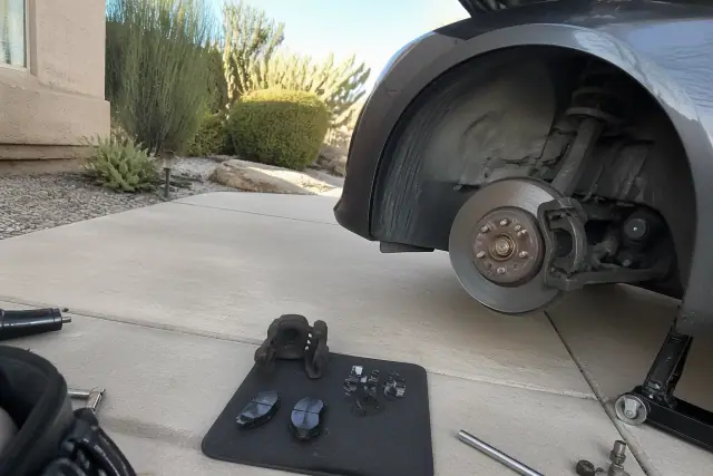 Mobile mechanic performing a brake repair on a car in a residential driveway in Tempe, AZ.
