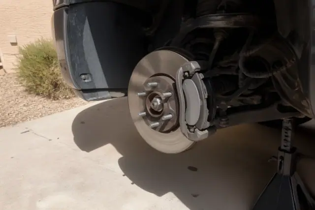 Mobile mechanic performing a brake repair with a removed wheel and new brake pads at a home in Surprise, AZ.