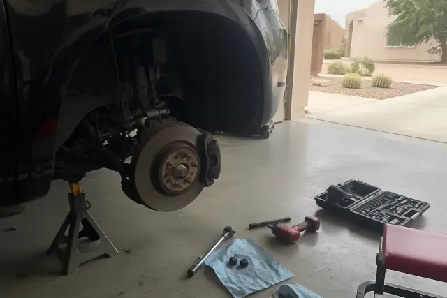 Vehicle elevated on jack stands in a Phoenix, AZ garage during a brake rotor and caliper repair.
