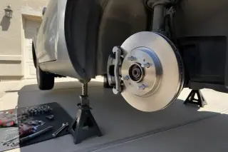 New brake rotor and caliper assembly on a car raised by jack stands in a Phoenix, AZ driveway.
