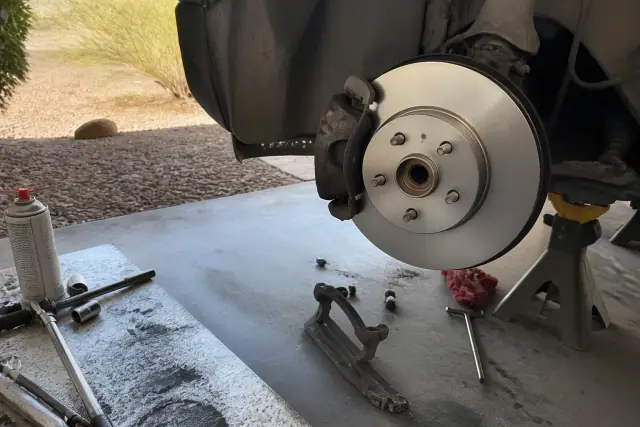 New brake rotor installed on a vehicle on jack stands in a residential garage in Phoenix, AZ.