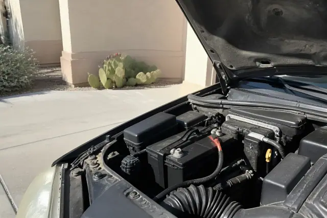 A new car battery with clean terminals and a secure hold-down bracket installed in a driveway in Phoenix, AZ.