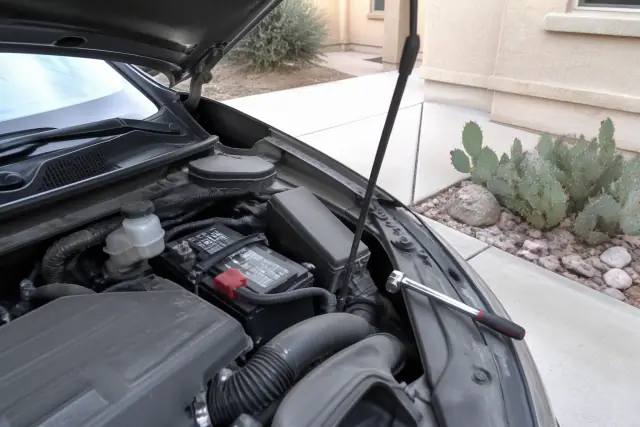 A mobile mechanic replacing a car battery in a residential driveway in Tempe, AZ.