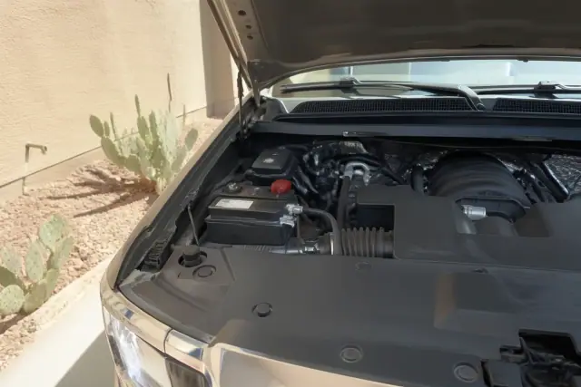 New car battery installed under the hood of a vehicle parked on a concrete pad at a home in Gilbert, AZ.