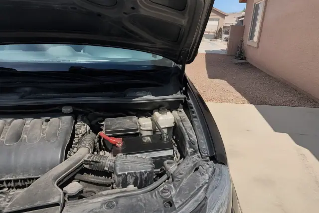 A mobile mechanic performing a car battery replacement on a vehicle in an Avondale, AZ residential driveway.