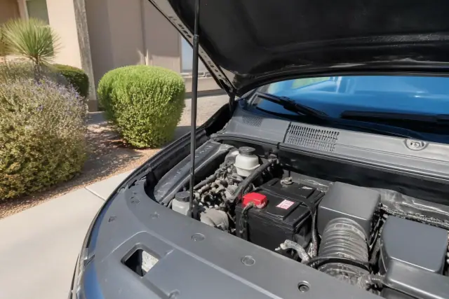 New car battery installed in a vehicle engine bay at a residential driveway in Chandler, AZ.
