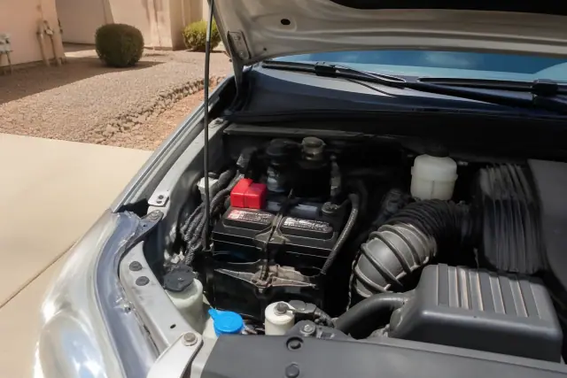 A new car battery installed in a vehicle parked on a concrete driveway in Goodyear, AZ.