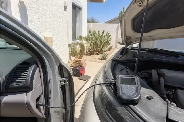 OBD-II scanner connected to a car engine for diagnostics at a residential home in Scottsdale, AZ.