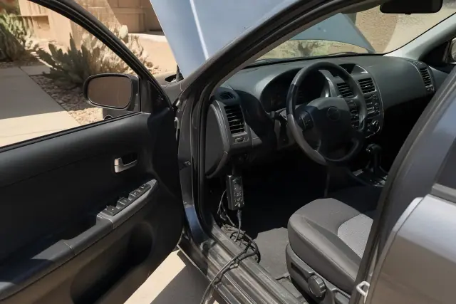 Technician performing car check engine diagnostics on a residential concrete pad in Mesa, AZ.