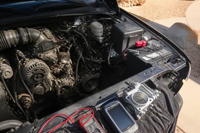 Engine bay showing the battery, alternator, and belts during a repair in Phoenix, AZ.