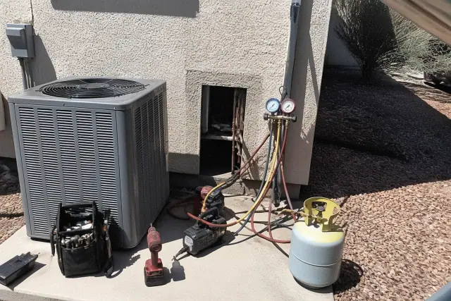 AC repair service with gauges and hoses connected to a residential unit on a concrete pad in Phoenix, AZ.