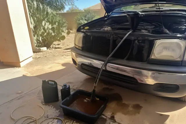 Car coolant replacement and radiator flush on a vehicle parked on a concrete driveway in Phoenix, AZ.
