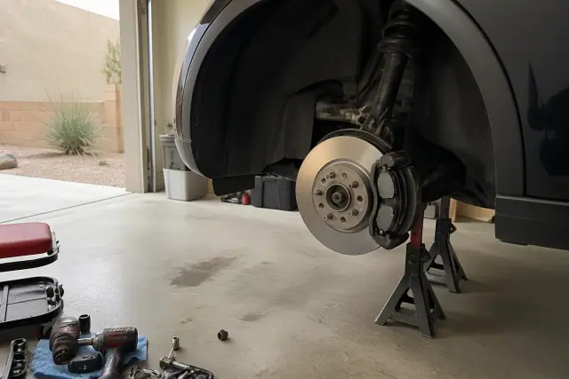 Car on jack stands with removed wheel and new brake pads in a Phoenix, AZ garage.