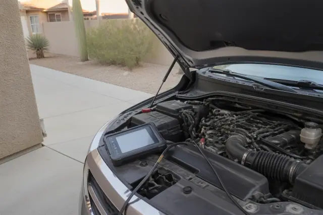 A technician performs an emissions system diagnosis on a vehicle engine in a residential driveway in Phoenix, AZ.