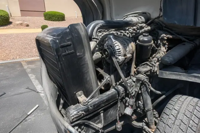 Mechanic installing a new alternator in a commercial vehicle at a job site in Phoenix, AZ.