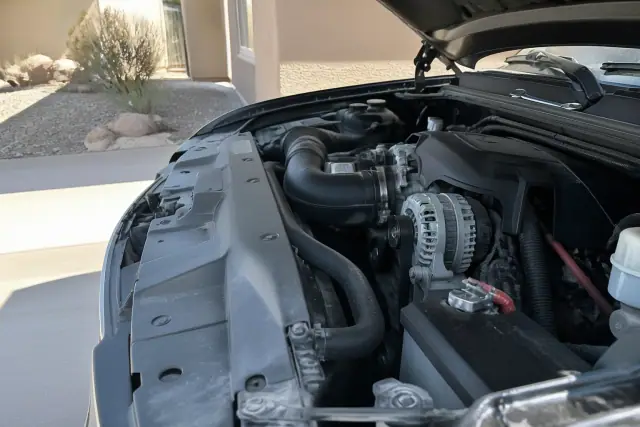 Completed alternator replacement on a vehicle engine in a residential driveway in Phoenix, AZ.