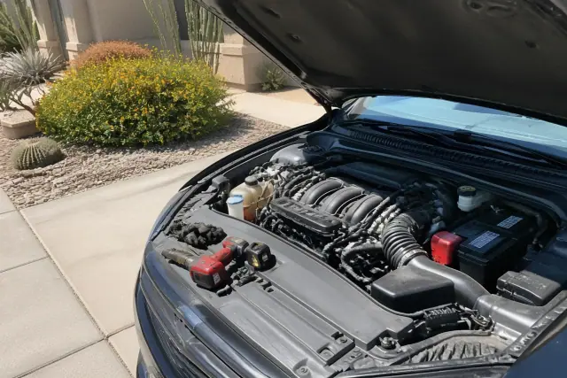 Car battery replacement in a Phoenix, AZ driveway with Group 24F and 35 batteries installed in an engine bay.