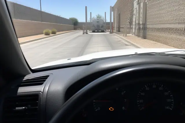 Illuminated check engine light on a car dashboard during a diagnostic test at a utility area in Phoenix, AZ.