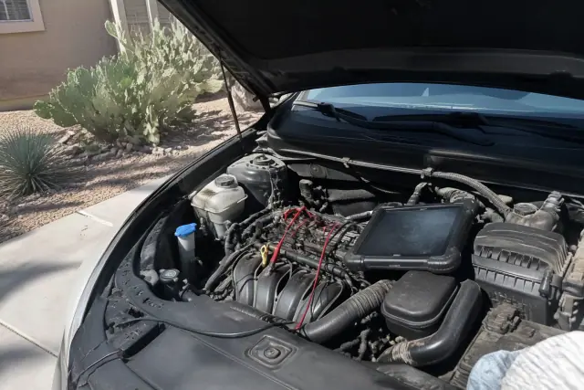 Open engine bay of a vehicle undergoing check engine light diagnostics in a Phoenix, AZ driveway.