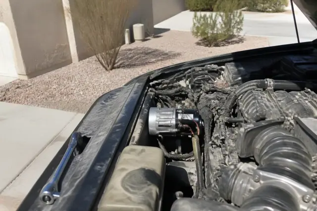 A new starter motor installed in a vehicle engine bay on a residential concrete pad in Phoenix, AZ.
