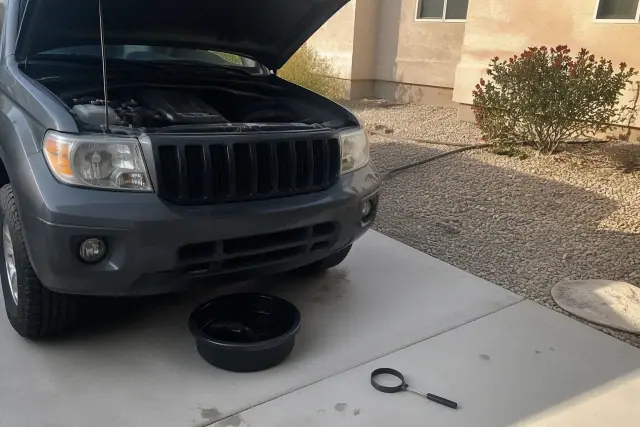 Mobile mechanic performing an oil change on a vehicle in a residential driveway in Surprise, AZ.