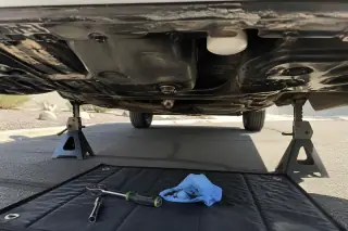 Clean oil filter and drain plug installed on a car engine underside in a Phoenix, AZ driveway.